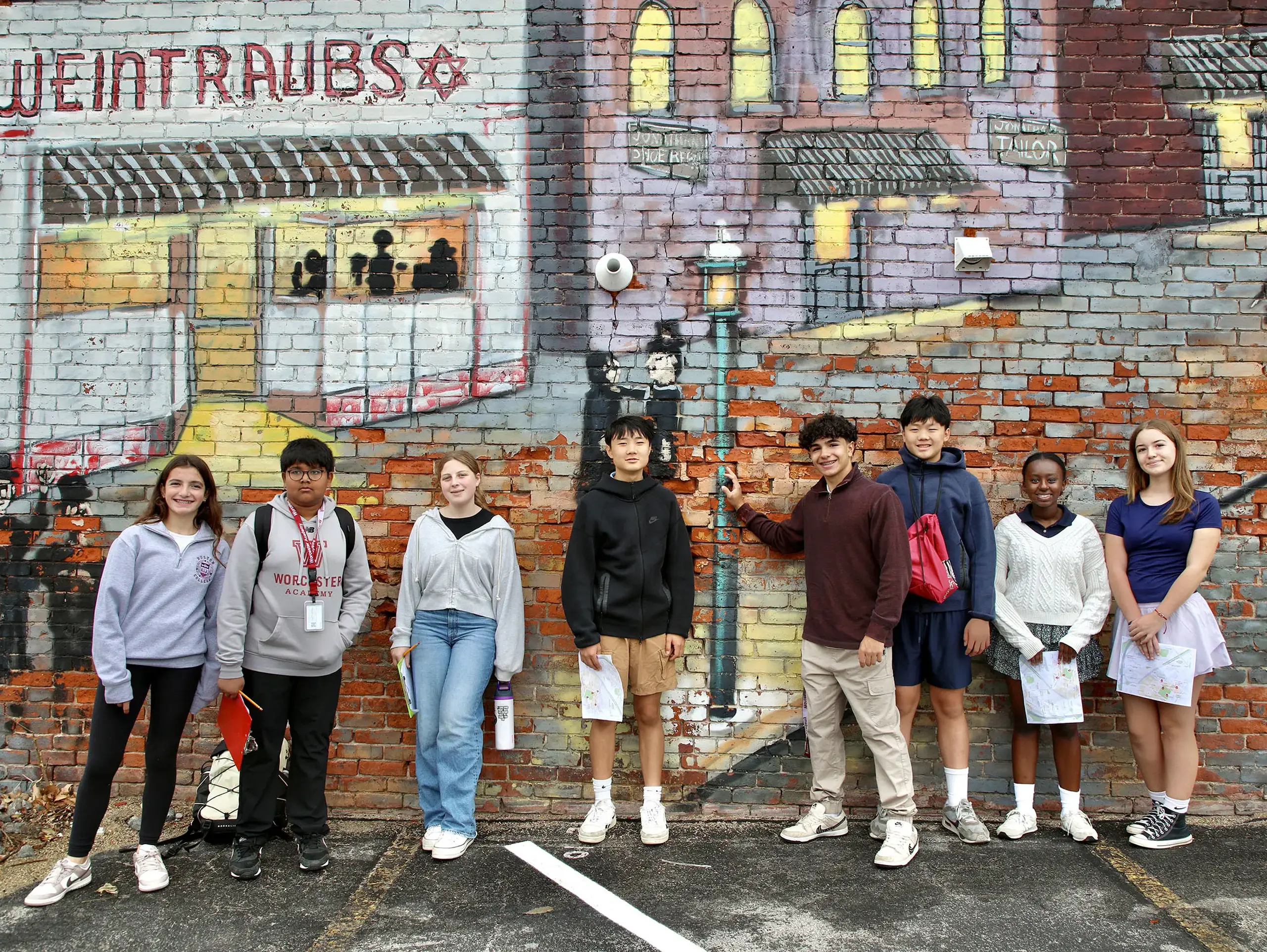 Students standing in front of a painted wall.