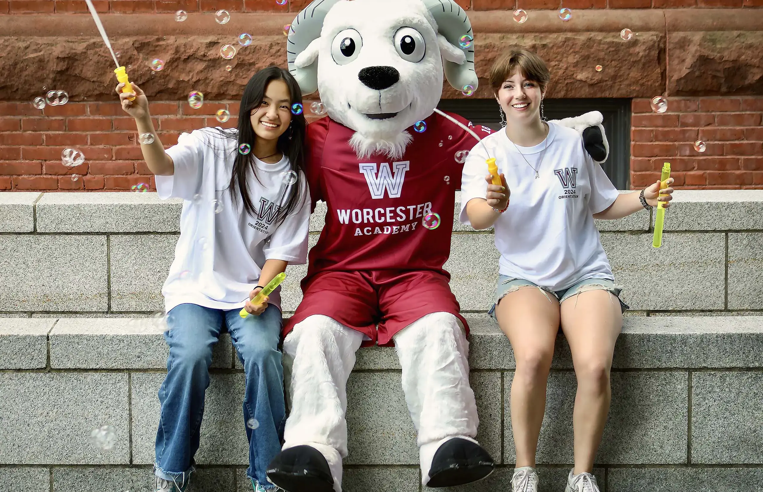 Worcester Academy students sitting with the mascot.