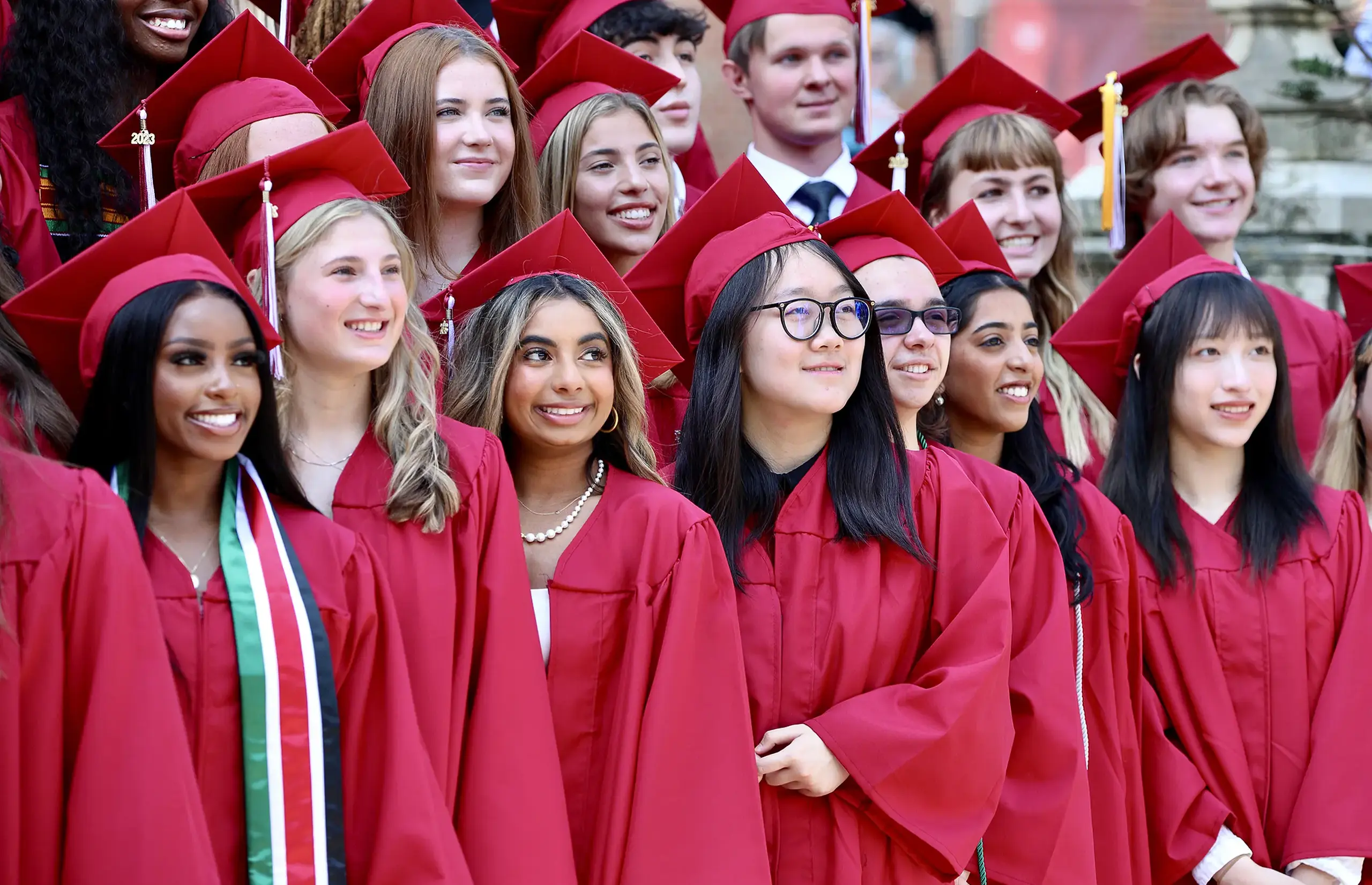 Upper School students graduating in red caps and gowns.