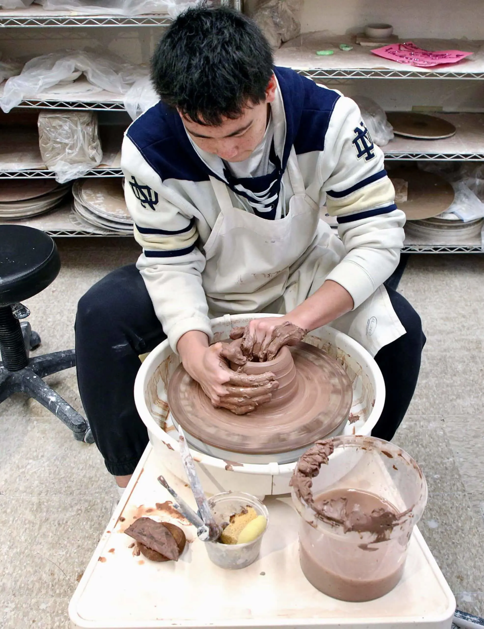 Worcester Academy Upper School student using a potter's wheel to make ceramics in a Visual Arts class.