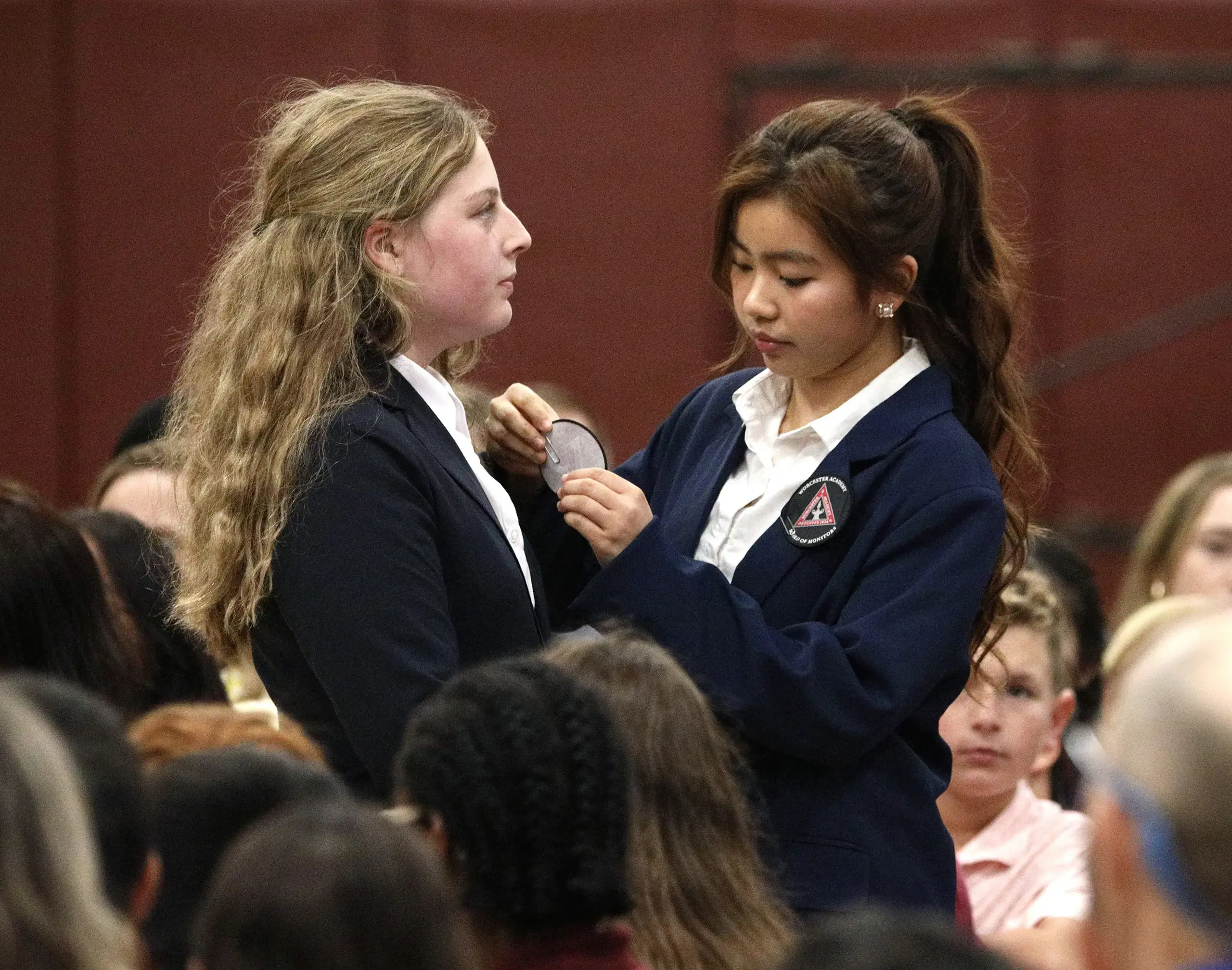 Students at BOM tapping ceremony; student pinning a jacket of another student.