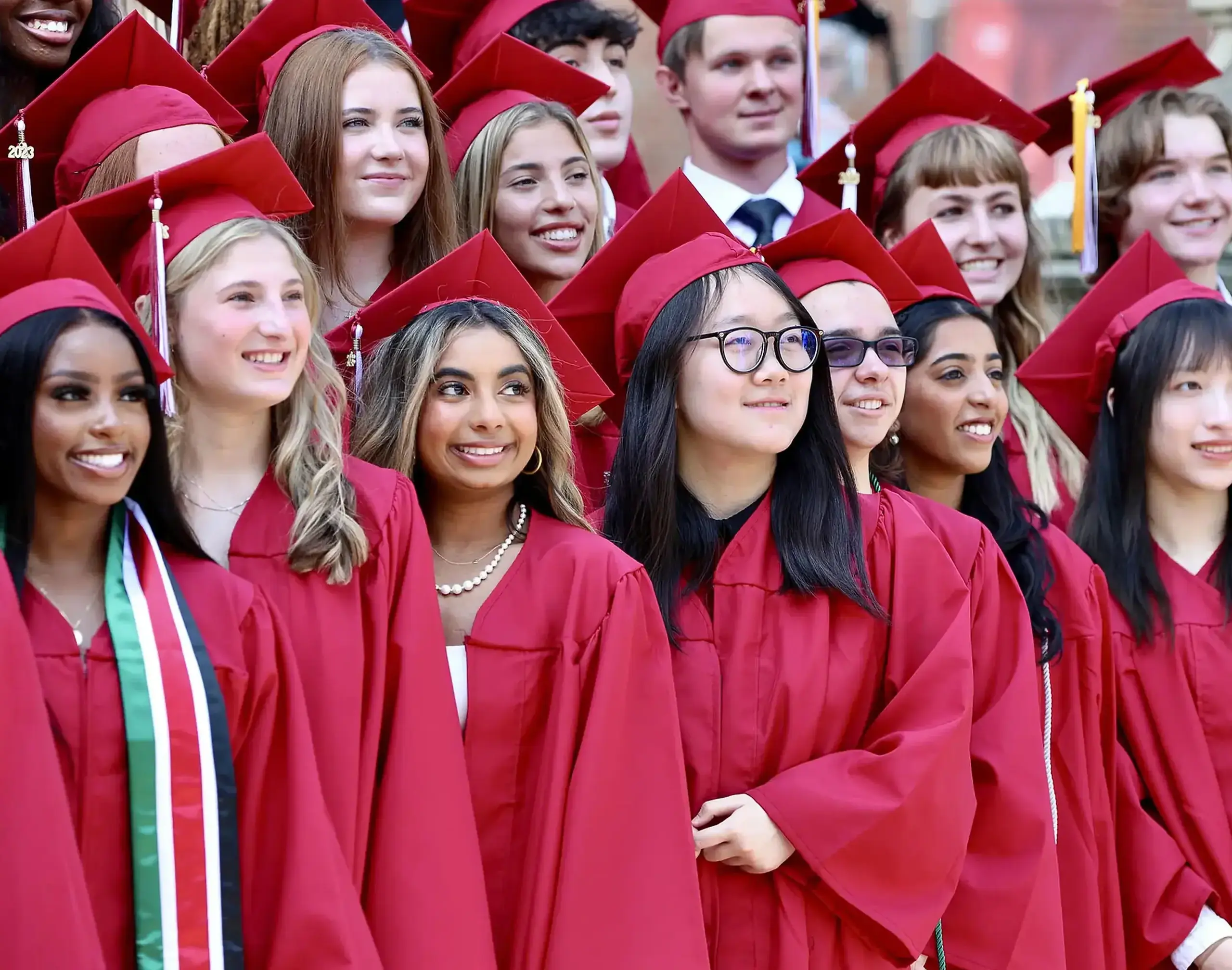 Upper School students graduating in red caps and gowns.