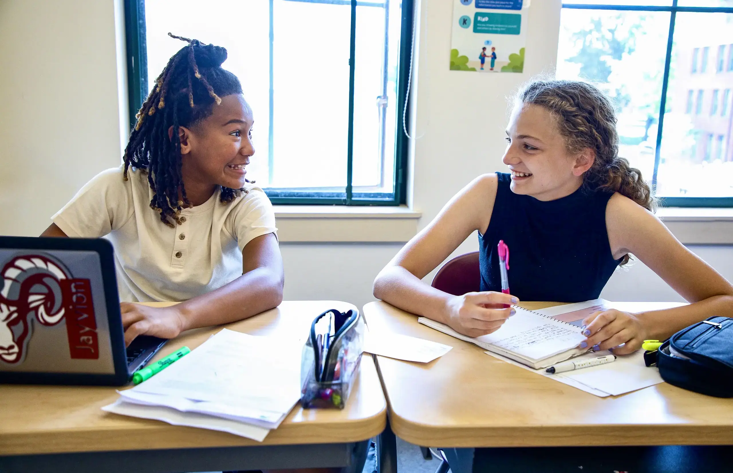 Two Middle School students at their desks smiling.