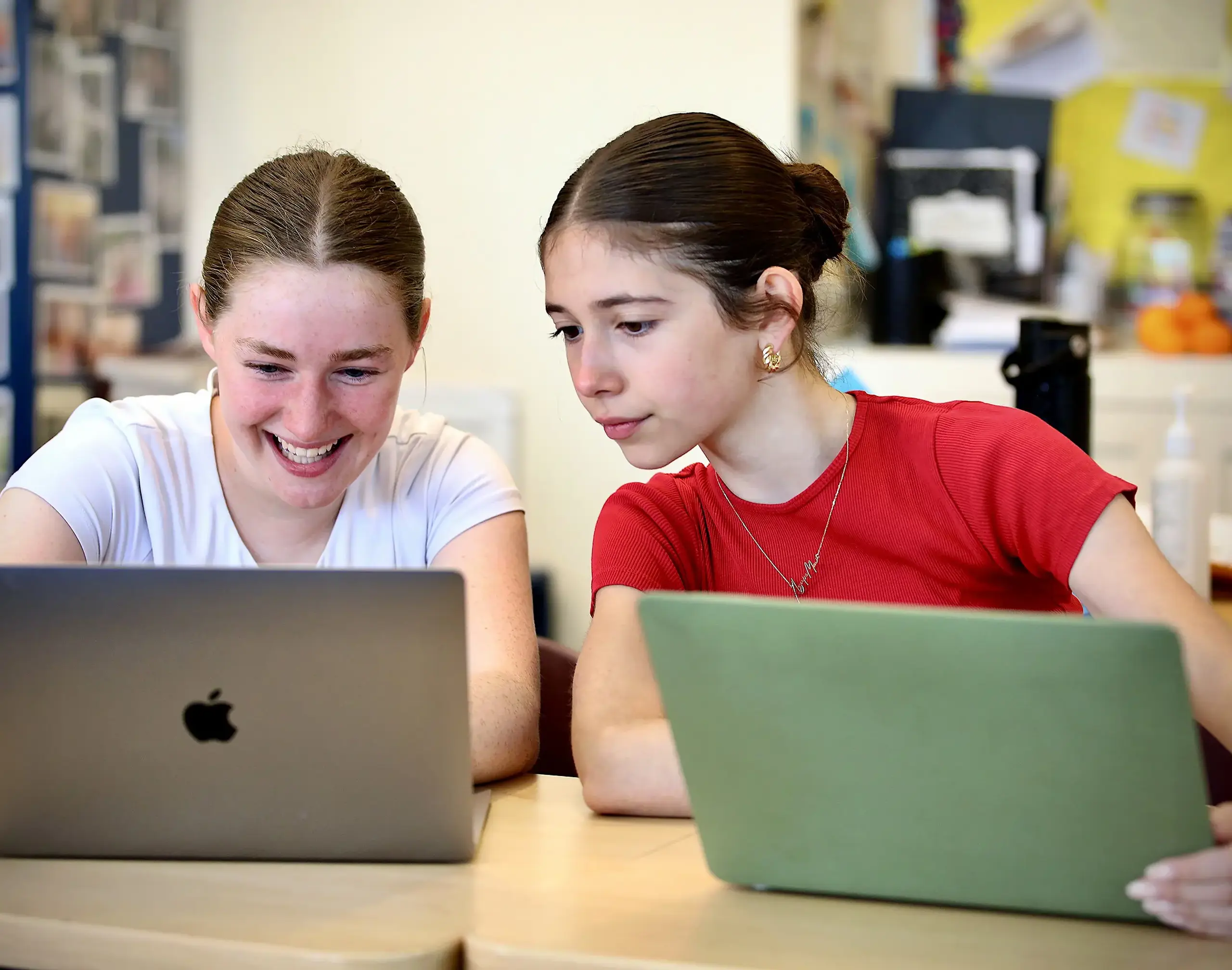 Two students looking at their laptop computers.