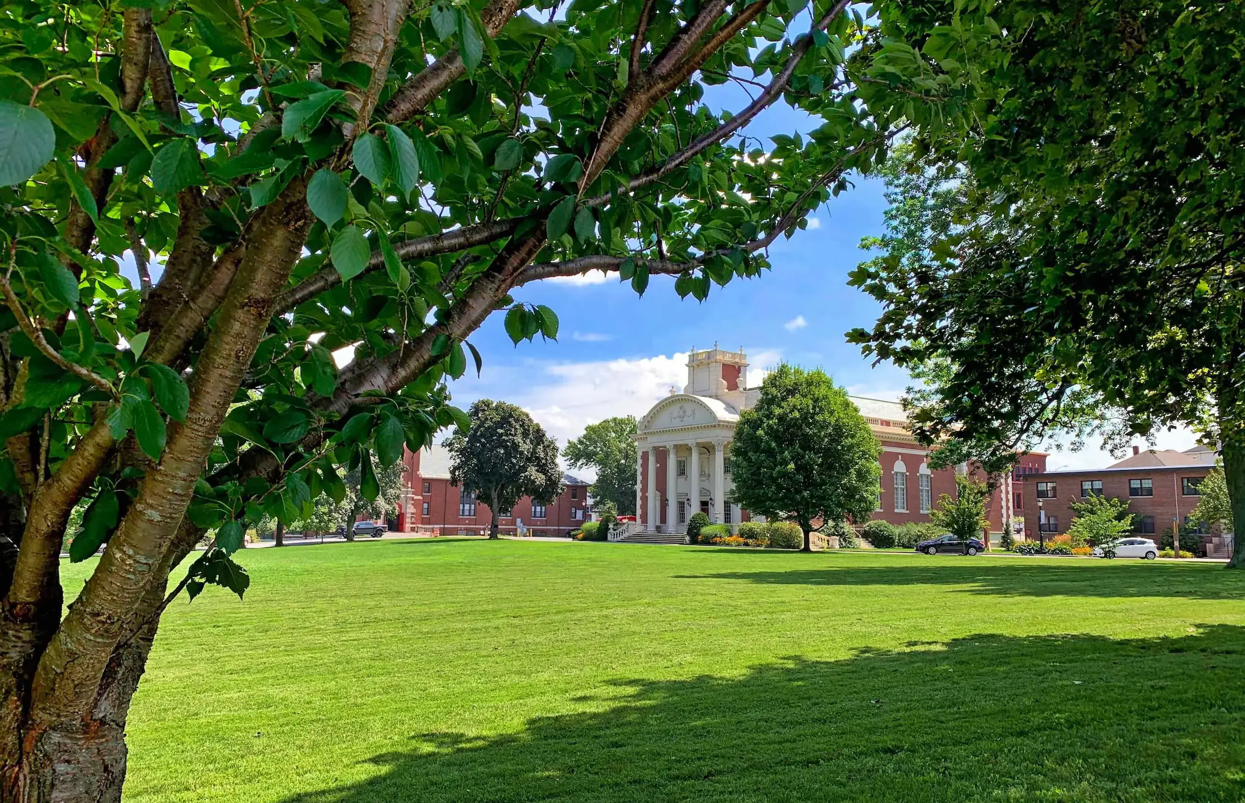 Worcester Academy Campus view of the Warner Building through leafy trees in spring