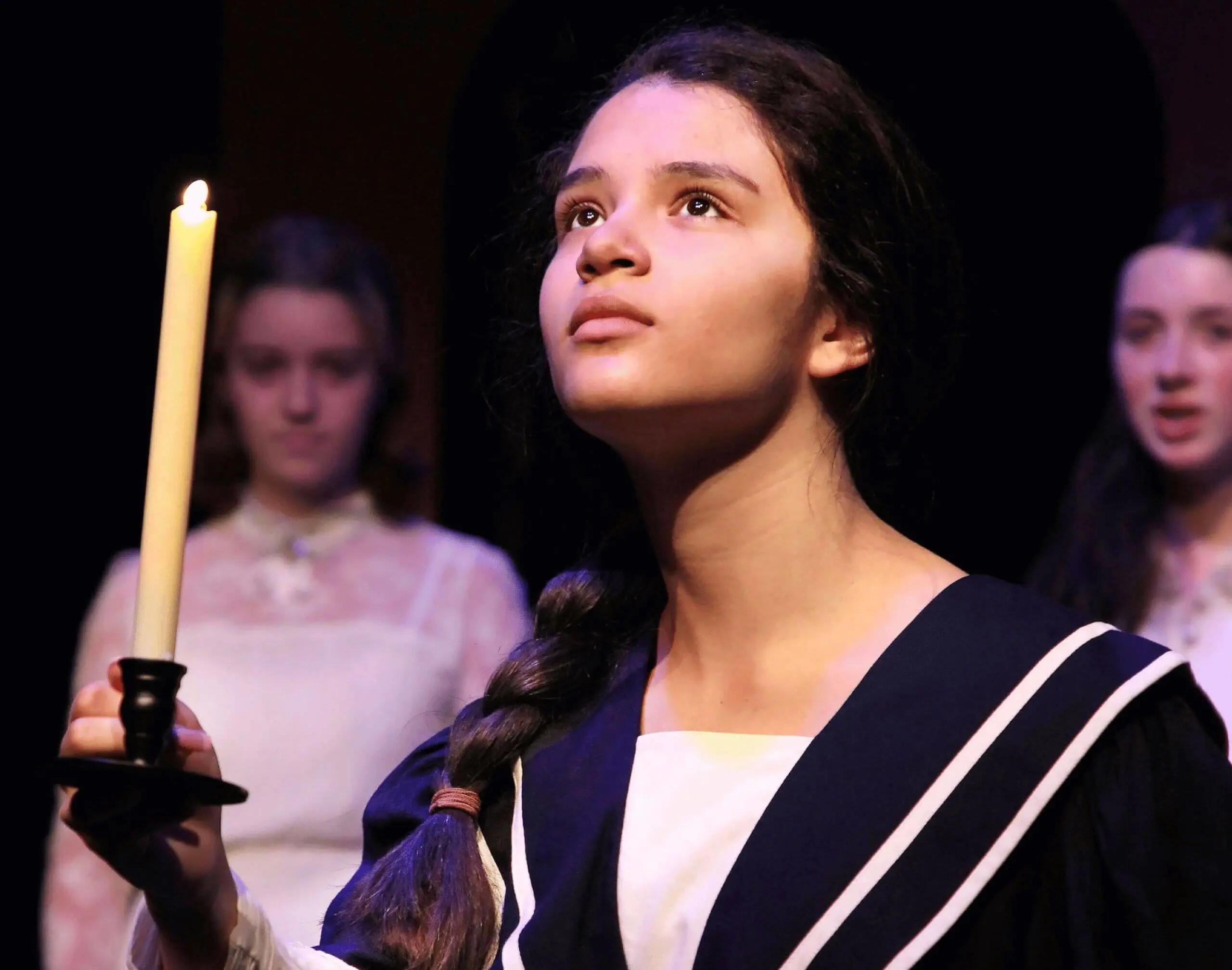 Worcester Academy Middle School student taking part in a play, holding a candle